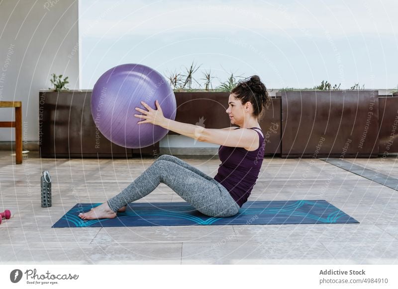 Flexible Sportlerin macht Sit-ups mit Fit-Ball auf der Terrasse Frau Dehnung Übung Passform-Ball Pilates Wellness Training Gleichgewicht Vitalität Wohlbefinden