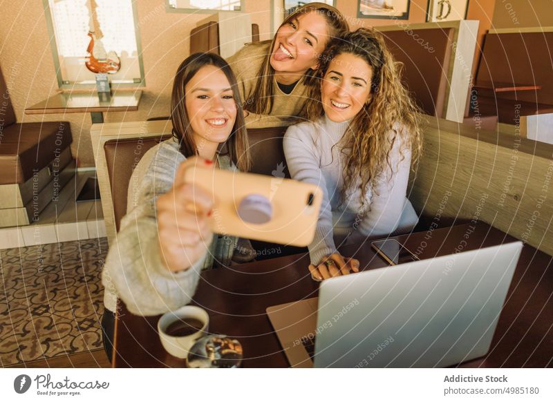 Positive Freunde machen ein Selfie im Cafe Frauen fotografieren Smartphone positiv Spaß Freundin Tisch Café Laptop ausspannen Apparatur Gerät Netbook teilen Tee