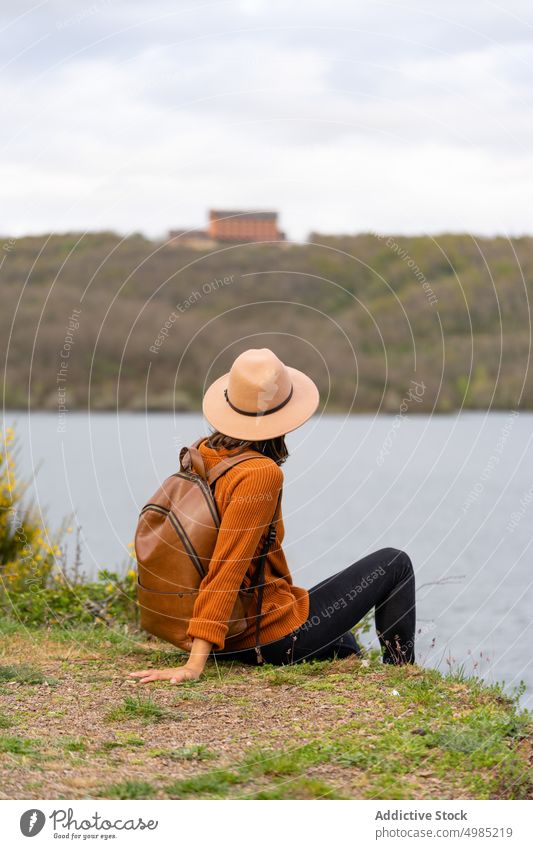 Anonyme Frau mit Rucksack am Ufer eines Flusses Reisender Flussufer Sommer Urlaub reisen Kälte palencia Spanien Natur Tourist Wochenende Wasser Abenteuer Hut
