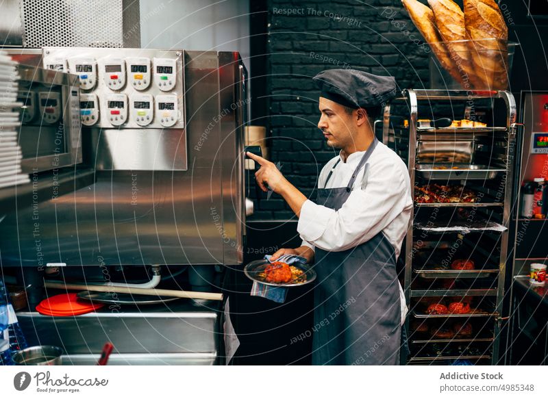 Mann stellt Zeitschaltuhr an einem Gerät im Restaurant ein Küchenchef Einstellung Vorrichtung Essen zubereiten zeigen Dienst Erinnerung Mitarbeiter