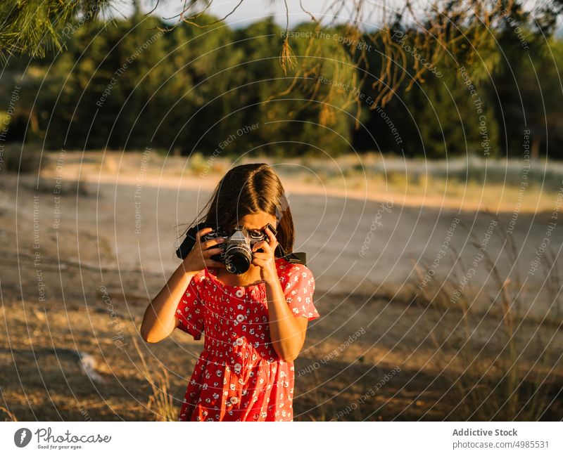 Kleines Mädchen fotografiert eine Landschaft an einem sonnigen Tag fotografierend Sommer Feld Natur Fotokamera Fotografie Glück Wiese schön bezaubernd rot Kind