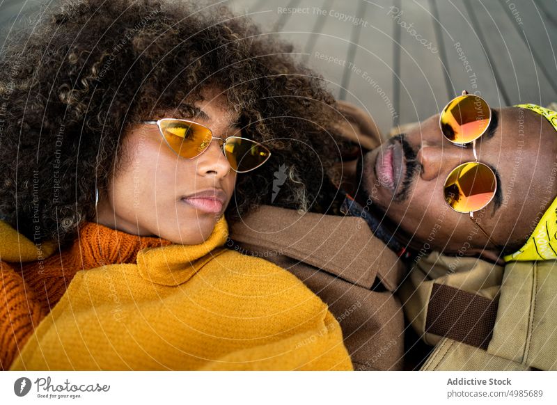 Sinnliches schwarzes Paar in bunter Kleidung auf dem Boden liegend Liebe farbenfroh trendy Mode Zusammensein Herbst ethnisch Afroamerikaner Angebot romantisch