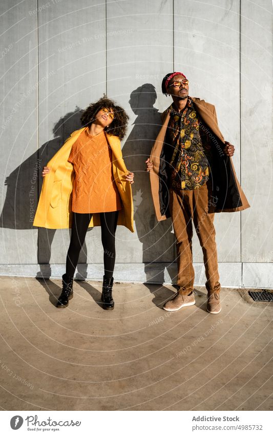 Trendiges Paar in stilvoller Kleidung auf der Straße stehend Frau Mode Mantel farbenfroh Mann Streetstyle Zusammensein Großstadt trendy ethnisch schwarz