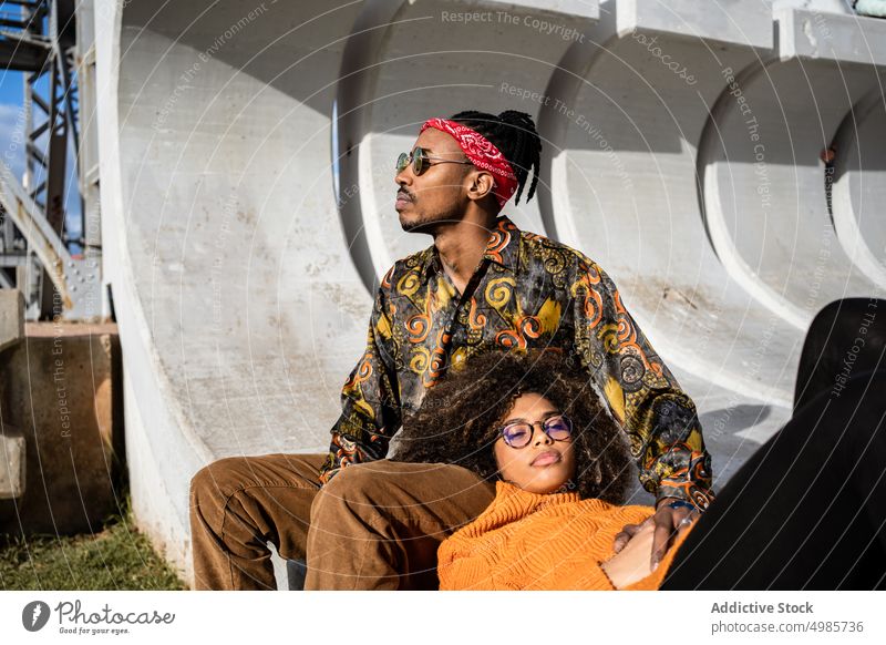 Schwarzes Paar auf einer Bank auf einem modernen Stadtplatz Lachen Glück urban Umarmen kuscheln Termin & Datum Zusammensein ethnisch schwarz Afroamerikaner