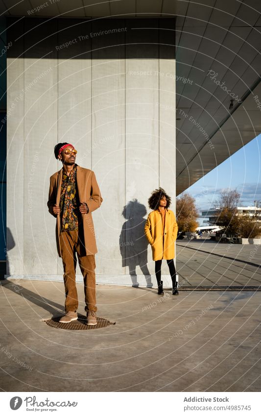 Selbstbewusste trendige Frau im Mantel auf der Straße mit ihrem Freund Mode farbenfroh Mann Paar Streetstyle Zusammensein Großstadt trendy ethnisch schwarz