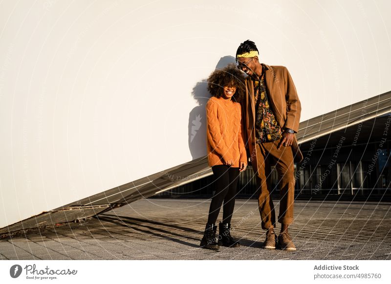 Moderner schwarzer Mann und Frau vor weißer Wand im Sonnenuntergang Paar Stil Großstadt ethnisch Zusammensein Streetstyle cool Afroamerikaner Zeitgenosse