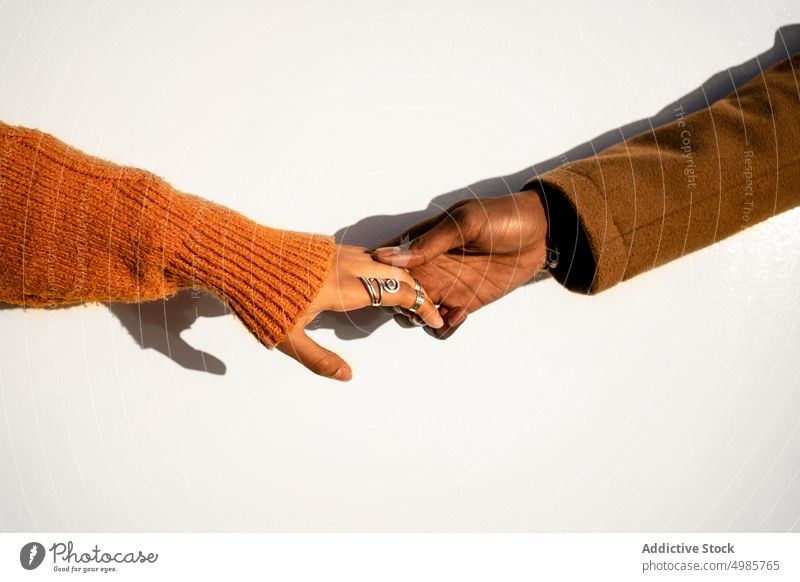 Crop-Paar in warmer Kleidung hält sanft die Hände Stil Liebe Händchenhalten Streetstyle Hand Strickwaren Pullover berühren schließen abstützen gestikulieren