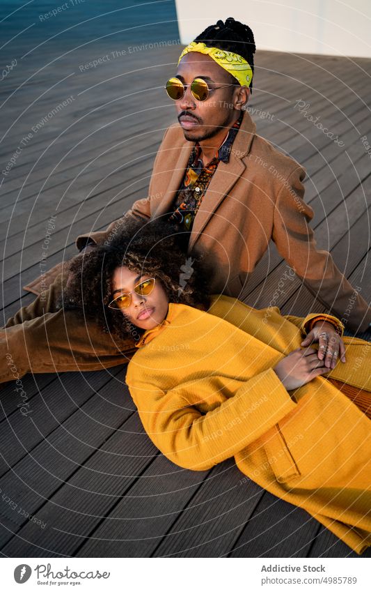 Sinnliches, modisches Paar auf Holzboden trendy farbenfroh Liebe Streicheln Zusammensein träumen ethnisch schwarz Afroamerikaner Farbe Afro-Look Rastalocken
