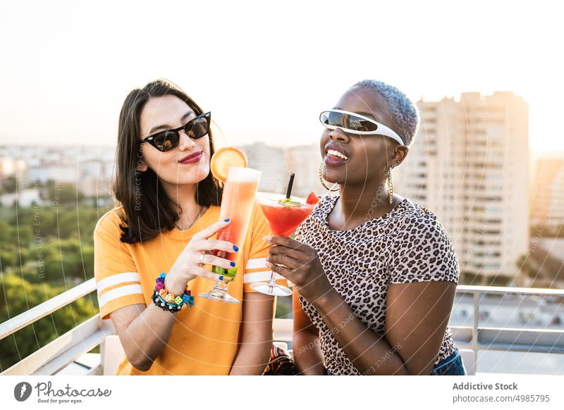 Multiethnisches Paar cooler lesbischer Frauen trinkt Cocktails trinken Sommer tropisch jubelt Röstung lgbt Erfrischung Freundin multiethnisch rassenübergreifend