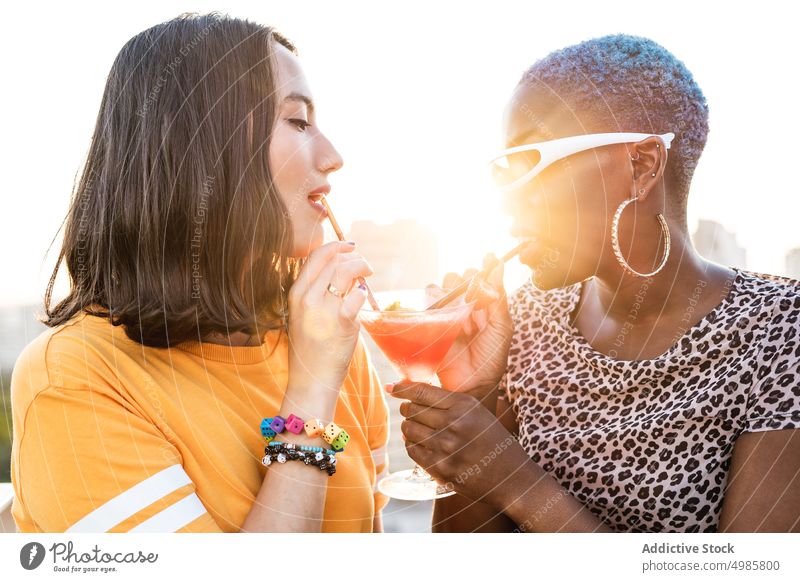 Multiethnisches Paar cooler lesbischer Frauen trinkt Cocktails trinken Sommer tropisch lgbt Erfrischung Freundin Stroh multiethnisch rassenübergreifend