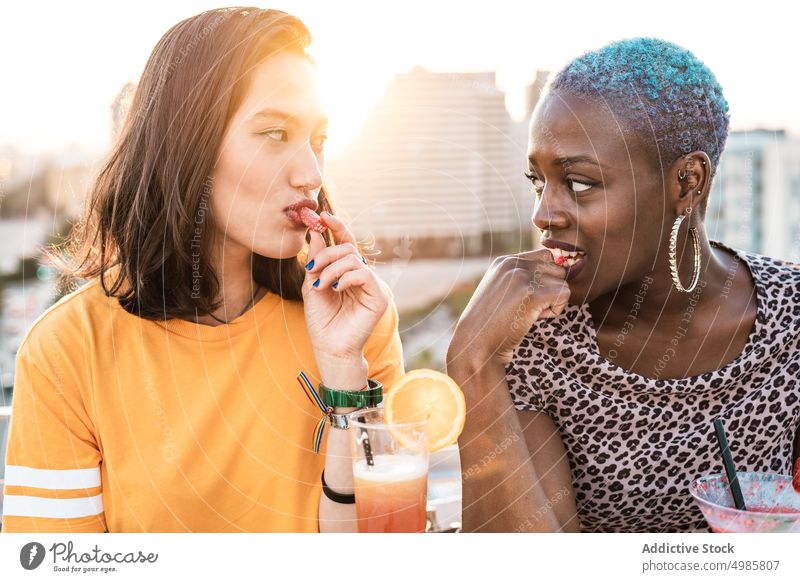 Multiethnisches Paar cooler lesbischer Frauen trinkt Cocktails trinken Sommer tropisch essen Bonbon lgbt Erfrischung Freundin multiethnisch rassenübergreifend