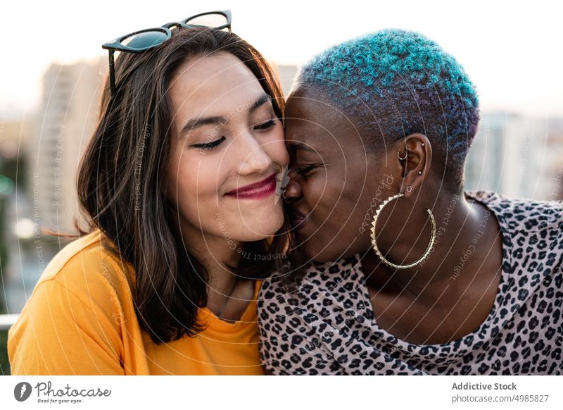 Multirassisches lesbisches Paar sitzt im Freien eng zusammen Nähe Partnerschaft Bonden Liebe lgbt Homosexualität Zusammensein jung multiethnisch