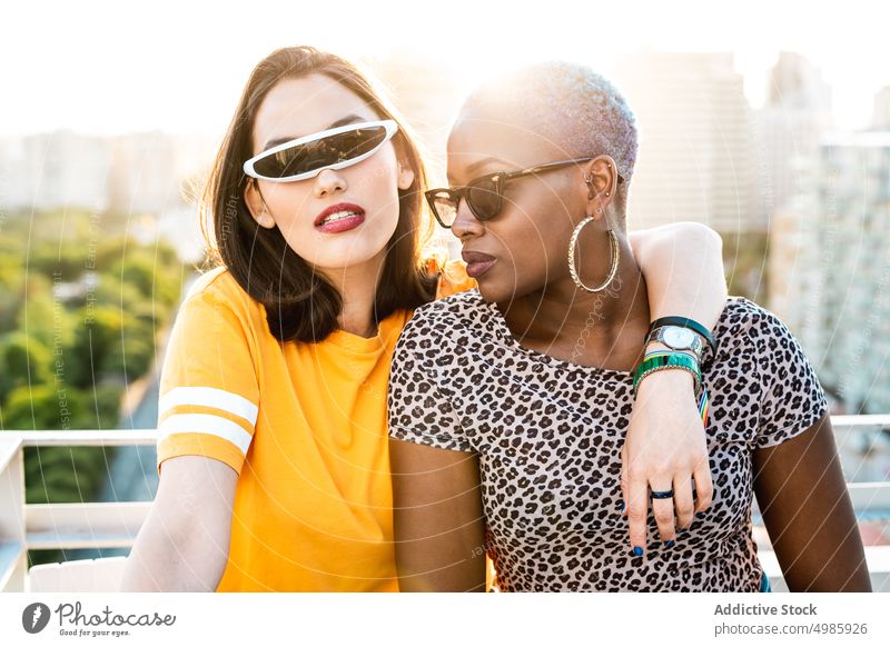 Stilvolles Paar von multirassischen lesbischen Frauen, die sich auf der Straße umarmen Umarmung trendy cool Liebe lgbt Sonnenbrille Freundin Umarmen