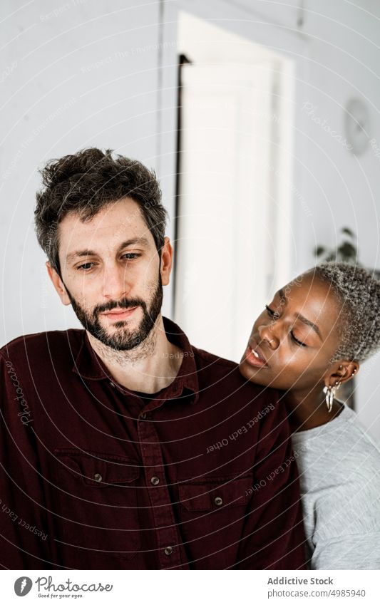 Zärtliches multiethnisches Paar, das sich zu Hause umarmt Liebe Umarmung Umarmen heimwärts kuscheln Partnerschaft lässig Lächeln Zusammensein romantisch