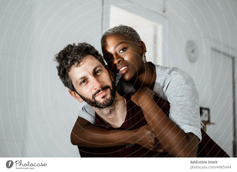 Zärtliches multiethnisches Paar, das sich zu Hause umarmt Liebe Umarmung Umarmen heimwärts kuscheln Partnerschaft lässig Lächeln Zusammensein romantisch