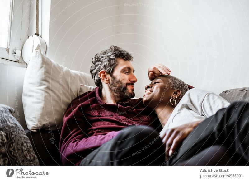 Junges multiethnisches Paar ruht sich auf dem Sofa aus kuscheln Liege schlafend Harmonie Windstille heimwärts Liebe sich[Akk] entspannen Wohnzimmer Bonden