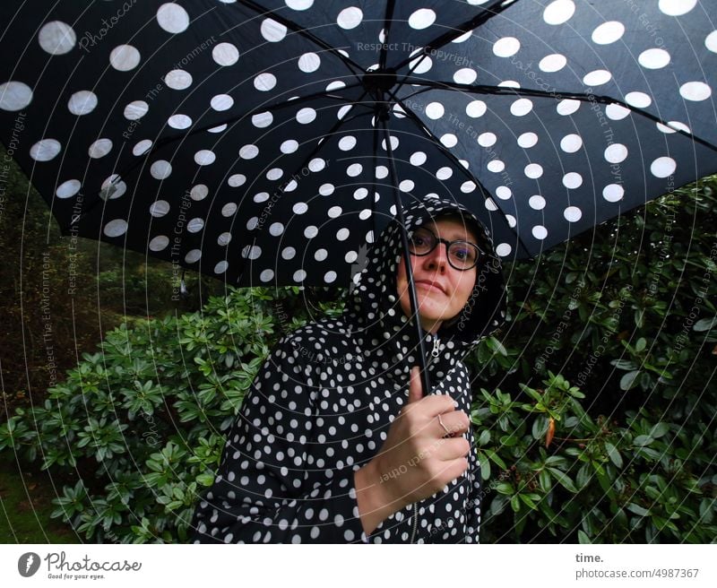 Unnamed Roads | Punktgewinnerin Frau Schirm Regenschirm gepunktet Regenjacke Park Busch Brille Blick in die Kamera weiblich halten schlechtes Wetter