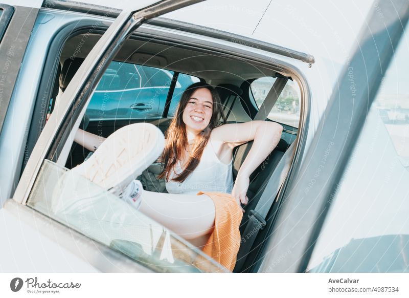 Junge Frau, die sich an einem sonnigen Tag auf dem Rücksitz eines Autos ausruht und lächelt. Person Genuss Freiheit Reise Wind Fenster Passagier Sitzen Lächeln