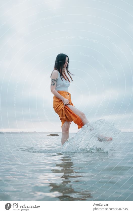 Frau steht auf trendigen Kleidern am Strand, während sie sich im Wasser spiegelt Person Fröhlichkeit Spaß sorgenfrei bunt Freiheit Freude rennen Silhouette nass