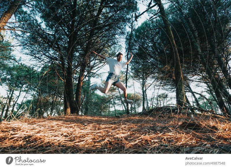 Junge Frau springt mit gespreizten Beinen in den Wald an einem sonnigen Tag. Freiheit und Freiheit Konzept Person Freude springen springend Fröhlichkeit Glück