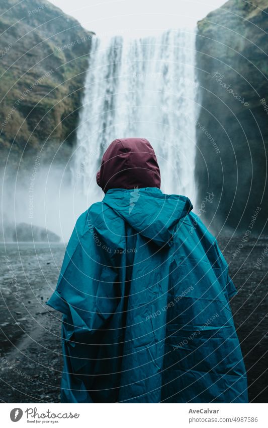Junger Reisender vor dem gewaltigen Skofagoss-Wasserfall auf der Insel Island an einem nebligen Regentag Person Frau Erkundung horizontal majestätisch Stehen