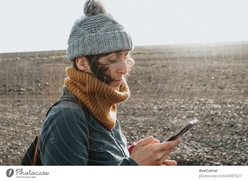 Junge Frau Reisende, die während des Sonnenuntergangs in Island mit Kopierraum das Schreiben auf dem Smartphone überprüft Anschluss horizontal eine Person