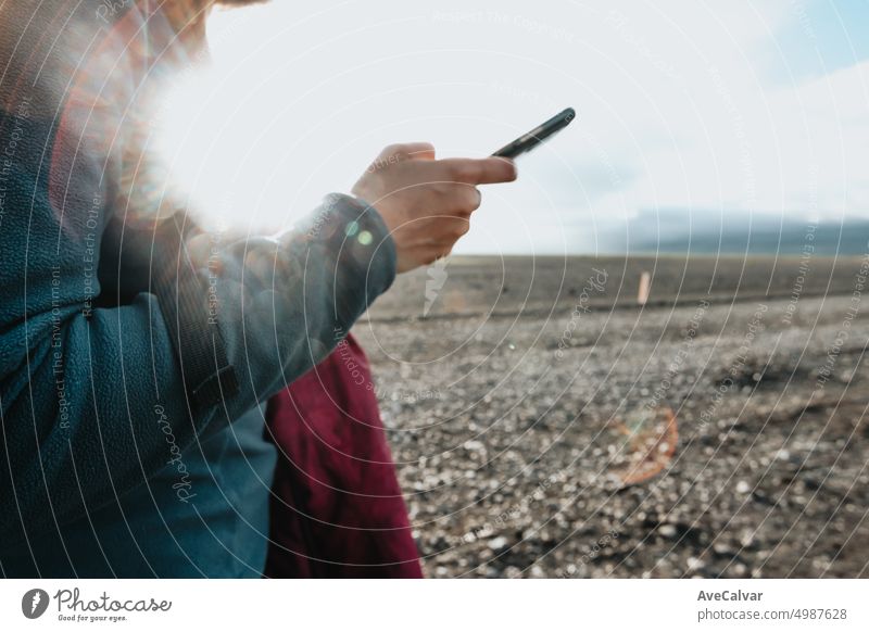 Junge Frau Reisende Überprüfung Schreiben auf Smartphone während Sonnenuntergang Tag in Island, Nahaufnahme Bild. Anschluss horizontal eine Person Teilen Ferien