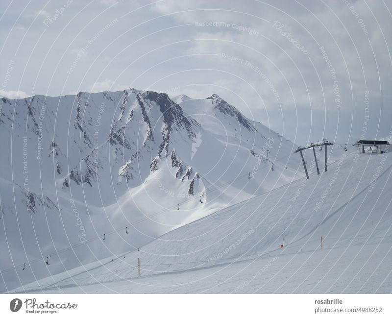 Winterlandschaft mit hohen Bergen im Skigebiet mit Sessellift Schnee kalt eingeschneit wolkig frieren eiskalt Kälte Winterzeit winterlich verschneit Landschaft