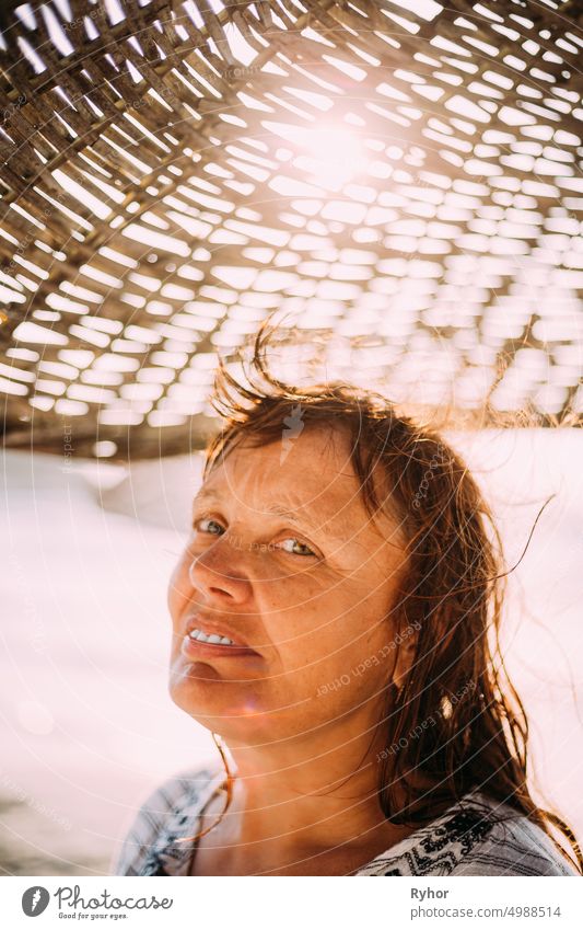 Erwachsene kaukasische Frau entspannt posiert unter Strand Sonnenschirm auf Sonnenuntergang. Urlaub am Meer Ozean Erwachsener attraktiv authentisch schön