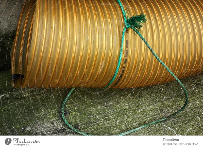 Dicke Röhre an langer Leine Rohr Kunststoff gelb Öffnung Schnur grün Knoten Betonboden Farbfoto Menschenleer Seil Hafen Dänemark