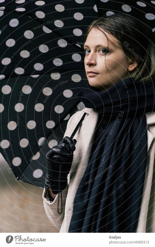 [HH Unnamed Road] Portrait einer jungen Frau mit gepunktetem Regenschirm Junge Frau Gepunktet Mantel Handschuhe Blick in die Kamera seitlich Schal schwarz beige