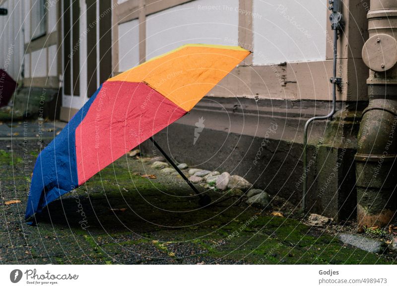 [HH Unnamed Road] Bunte Regenschirme stehen aufgespannt auf dem Boden vor einer Hauswand Schatten Hausmauer bunt gemischt Wand Außenaufnahme Fassade Farbfoto