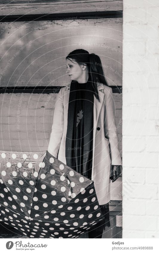 [HH Unnamed Road] Junge Frau mit gepunktetem Regenschirm steht vor einer Wand und blickt zur Seite Mensch Wetter Schirm nass schlechtes Wetter Straße