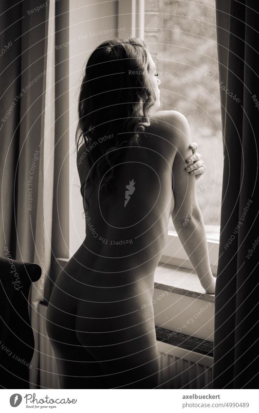 nackte junge Frau am Fenster stehend im Retrostil Aussehen Ausschau haltend anstarrend Sehnsucht Stehen Raum heimwärts Appartement im Innenbereich Körper