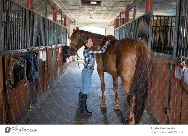 Frau kümmert sich um ihr Pferd im Stall Ranch Sattel Pferdestall eine Person Menschen Erwachsener Scheune Tiere Ländliche Szene Dompteur Pflege Bauernhof Hobby