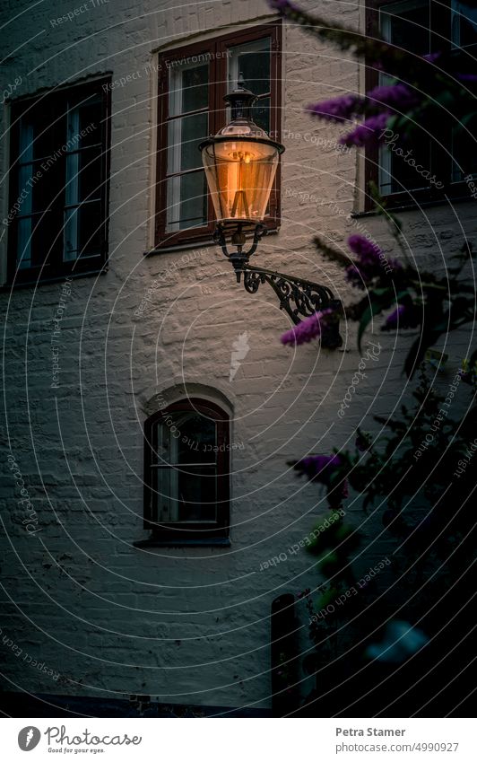 Nachtleben | Leuchtende Laterne an einer Hauswand Lampe Strom Energie Hausfassade Licht Straßenbeleuchtung Beleuchtung Fenster Fassade Architektur Gebäude Wand