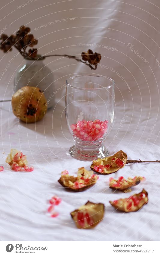 Vertikaler Schuss von Granatapfelkernen auf einem Trinkglas zur Herstellung von frischem Fruchtsaft als erfrischendes Sommergetränk Erfrischung Wohlbefinden