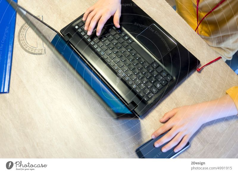 Die Hände eines Jungen tippen auf einer Laptop-Tastatur über einem rustikalen Holztisch. Prüfung Hausaufgabe Schule Schüler Hand Technik & Technologie Person