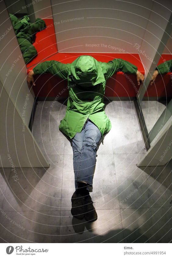 ArtStadtTour | ShowdownShow Umkleide Frau sitzen grün Regenmantel Jeans Spiegel Raum Fußboden Parkett Schauspielerin düster Schatten Kunstlicht Kabine Kapuze