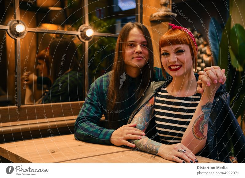 Lächelndes Paar in einem Café, das in die Kamera schaut. Sie ist rothaarig und hat einen Pin-up-Stil Erwachsener schön Bonden Freund Feier heiter Club