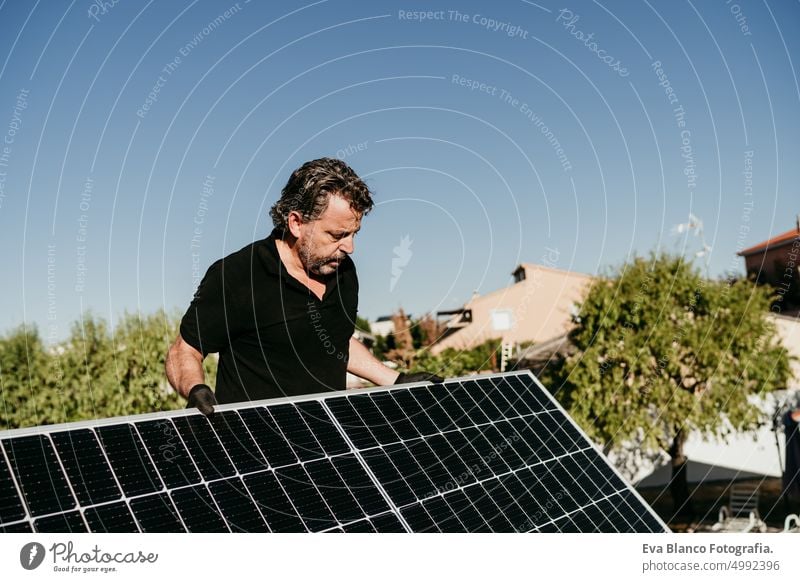 reifen Techniker Mann hält Sonnenkollektoren auf Hausdach für Selbstverbrauch Energie. Erneuerbare Energien und grüne Energie Konzept Ökostrom Dach Photovoltaik