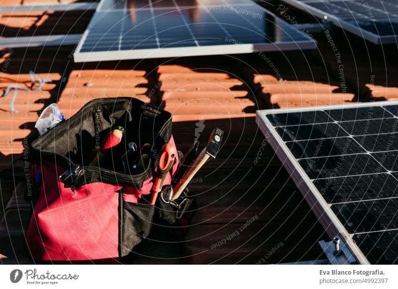 Tasche mit Technikerwerkzeug und Solarpanel auf dem Dach bei Sonnenaufgang Erneuerbare Energien und grünes Energiekonzept Sonnenkollektoren Ökostrom