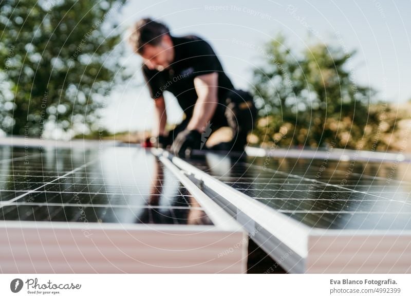reifen Techniker Mann Montage von Sonnenkollektoren auf Hausdach für den Eigenverbrauch Energie. Erneuerbare Energien und grüne Energie Konzept. Fokus auf Vordergrund