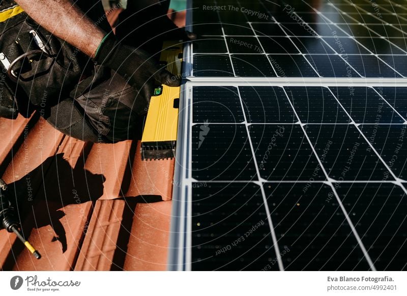 close up Hände der reifen Techniker Mann mit Ebene auf Sonnenkollektoren auf Hausdach für Selbstverbrauch Energie. Erneuerbare Energien und grüne Energie Konzept