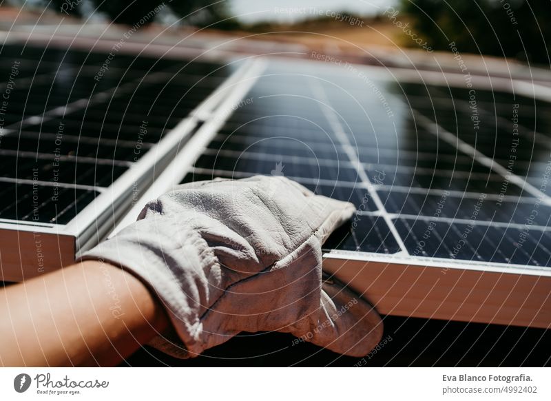 Nahaufnahme der Hand eines reifen Technikers, der Sonnenkollektoren auf dem Hausdach für den Eigenverbrauch von Energie berührt. Erneuerbare Energien und grüne Energie Konzept