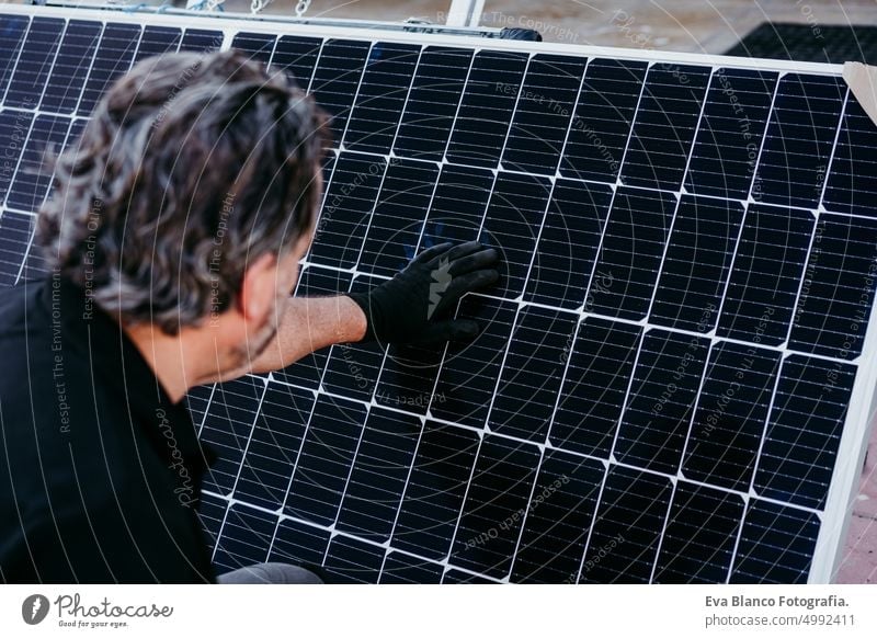 Rückenansicht eines reifen Technikers, der Sonnenkollektoren für den Eigenverbrauch von Energie überprüft. Erneuerbare Energien und grünes Energiekonzept