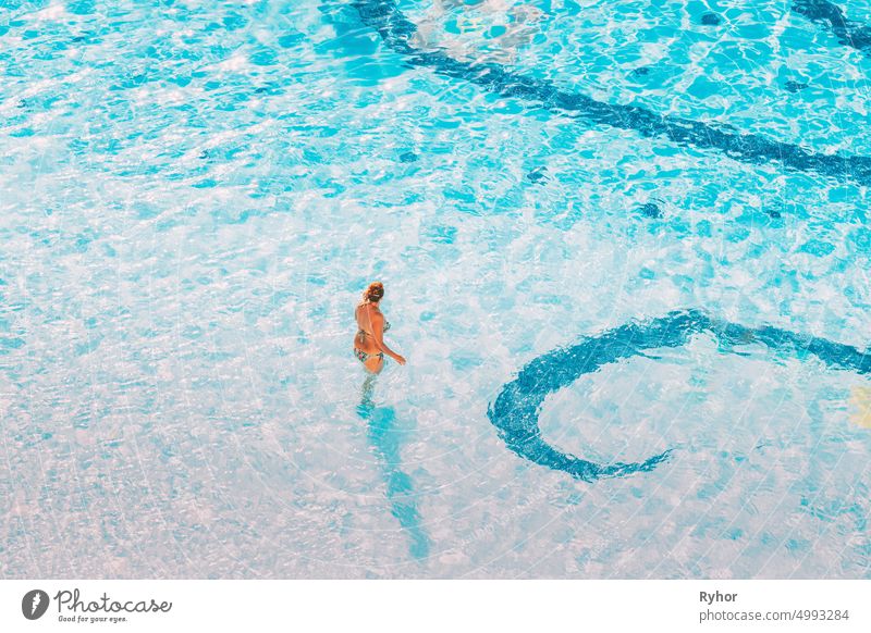 Erwachsene kaukasische Frau Frau stehend im Hotel Schwimmbad in sonnigen Sommertag. Urlaub im Hotel aktiv aktiver Lebensstil Erwachsener allein authentisch