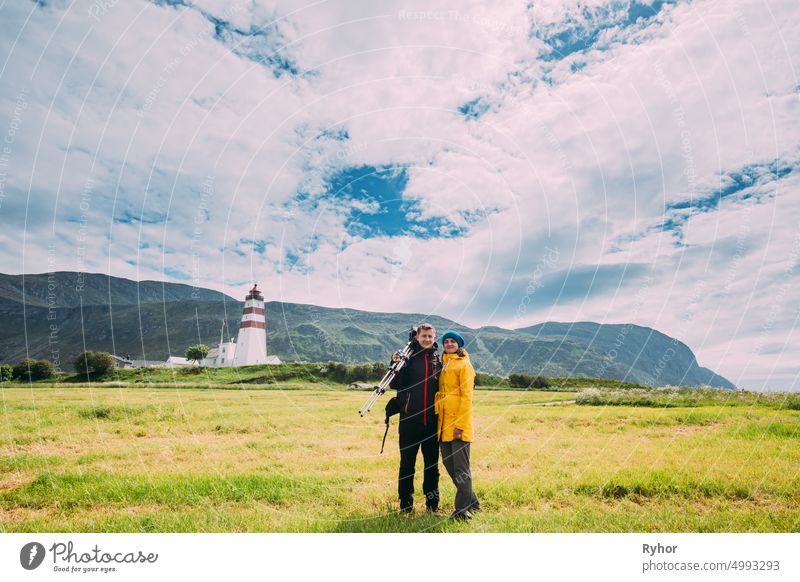 Alnesgard, Godoya, Norwegen. Mann und Frau Junge Erwachsene Kaukasische Touristen Reisende Paar Posing gegen alte Alnes Leuchtturm im Sommer Tag in Godoy Island in der Nähe von Alesund Stadt. Alnes Fyr
