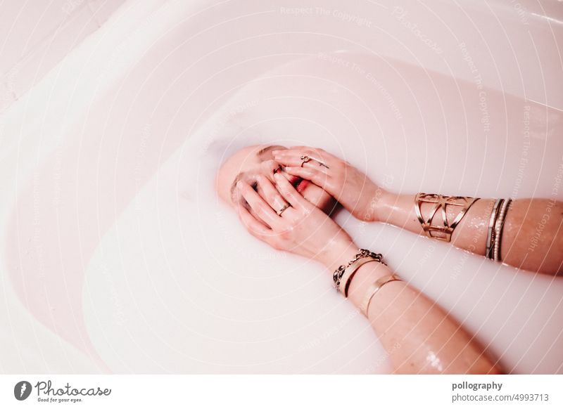 Eine Frau taucht in der Badewanne unter milchiger Flüssigkeit, bedeckt das Gesicht mit Händen ausgewählt verschwommen Produkte künstlerisch badewanne Wasser