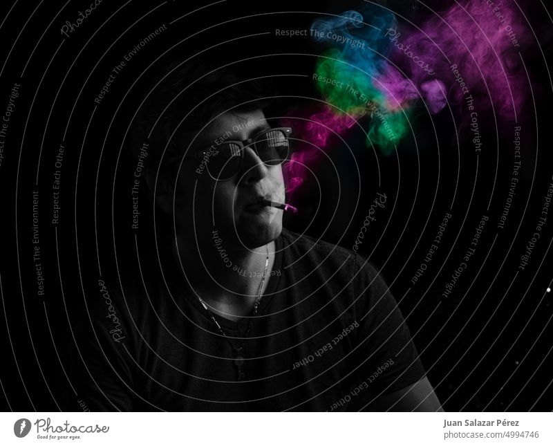 Stilvoller Mann raucht eine Zigarette mit farbigem Rauch Porträt Farbfoto Erwachsene Rauchen vertikal Nikotin Raucherin Farbe blau Dampf Laster Coolness